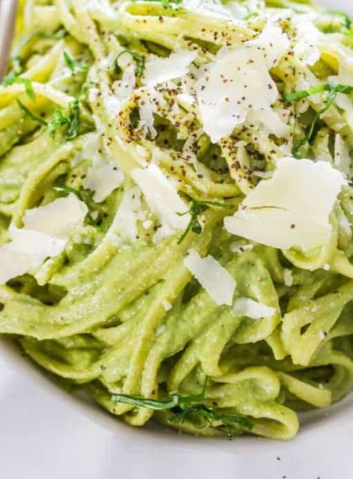 spinach avocado sauce topped pasta with grated parmesan cheese and black pepper sprinkled on top.